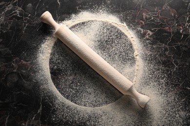 Imprint of plate on black marble table with flour and rolling pin, top view