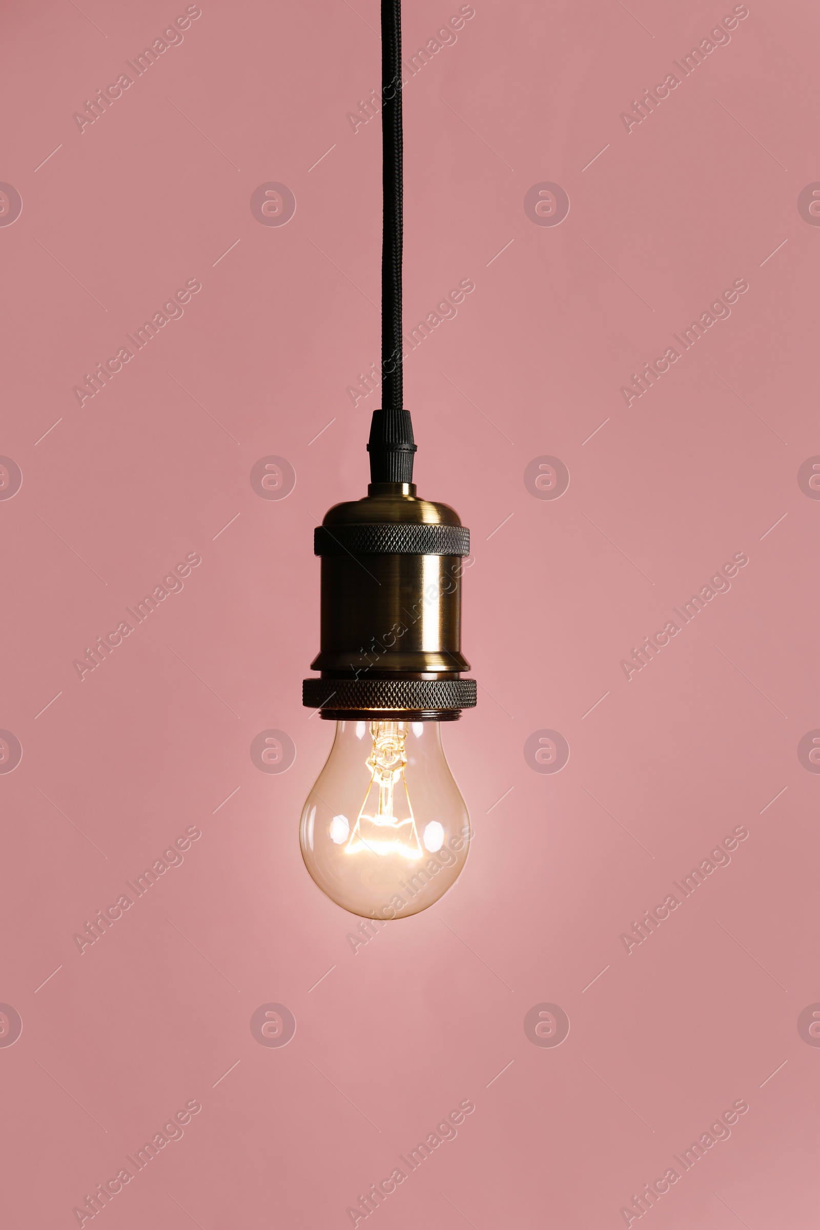 Photo of Hanging modern lamp bulb against pink background