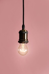 Hanging modern lamp bulb against pink background