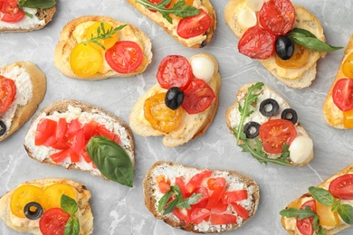 Delicious tomato bruschettas on light grey marble background, flat lay