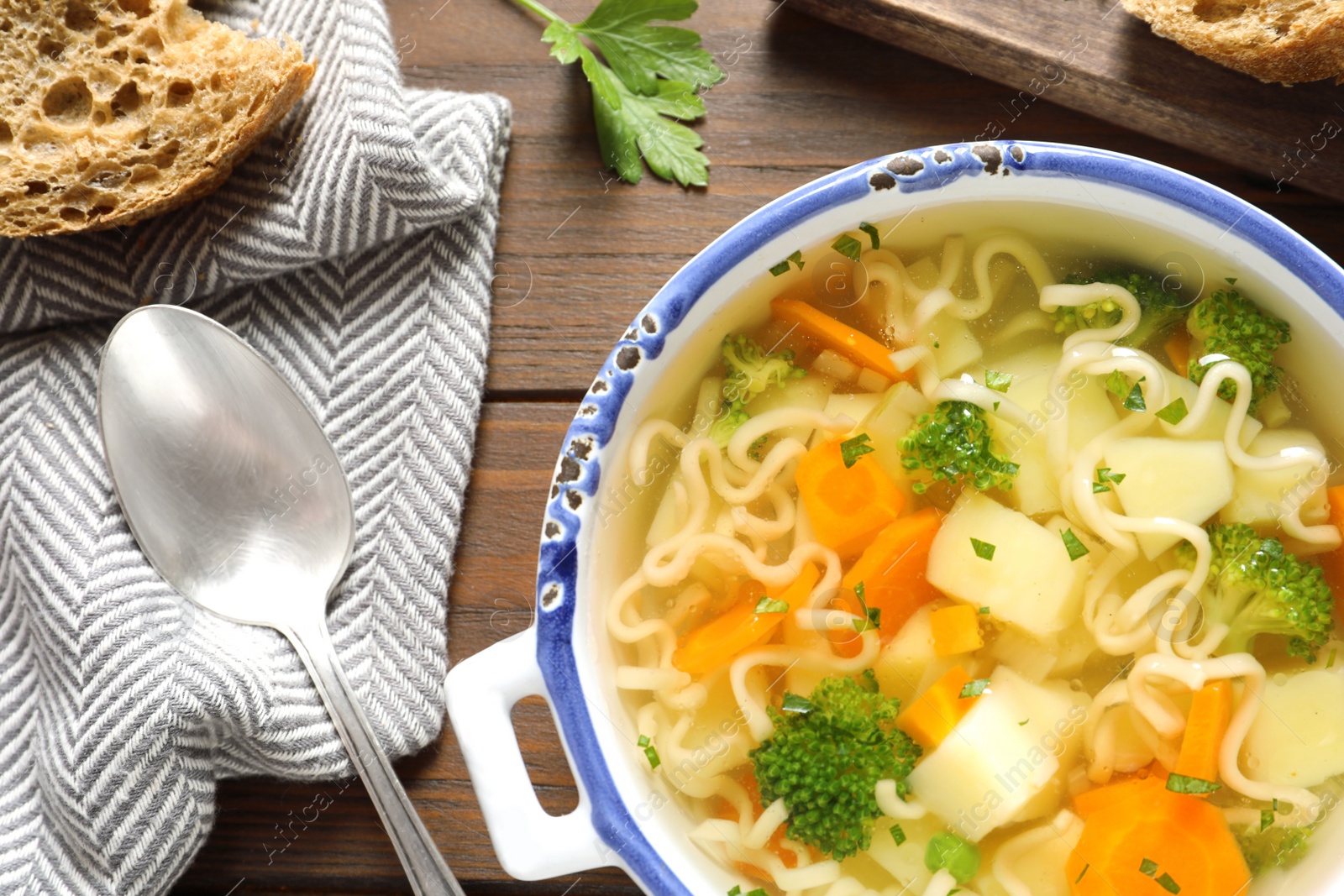 Photo of Dish of fresh homemade vegetable soup served on wooden table, flat lay