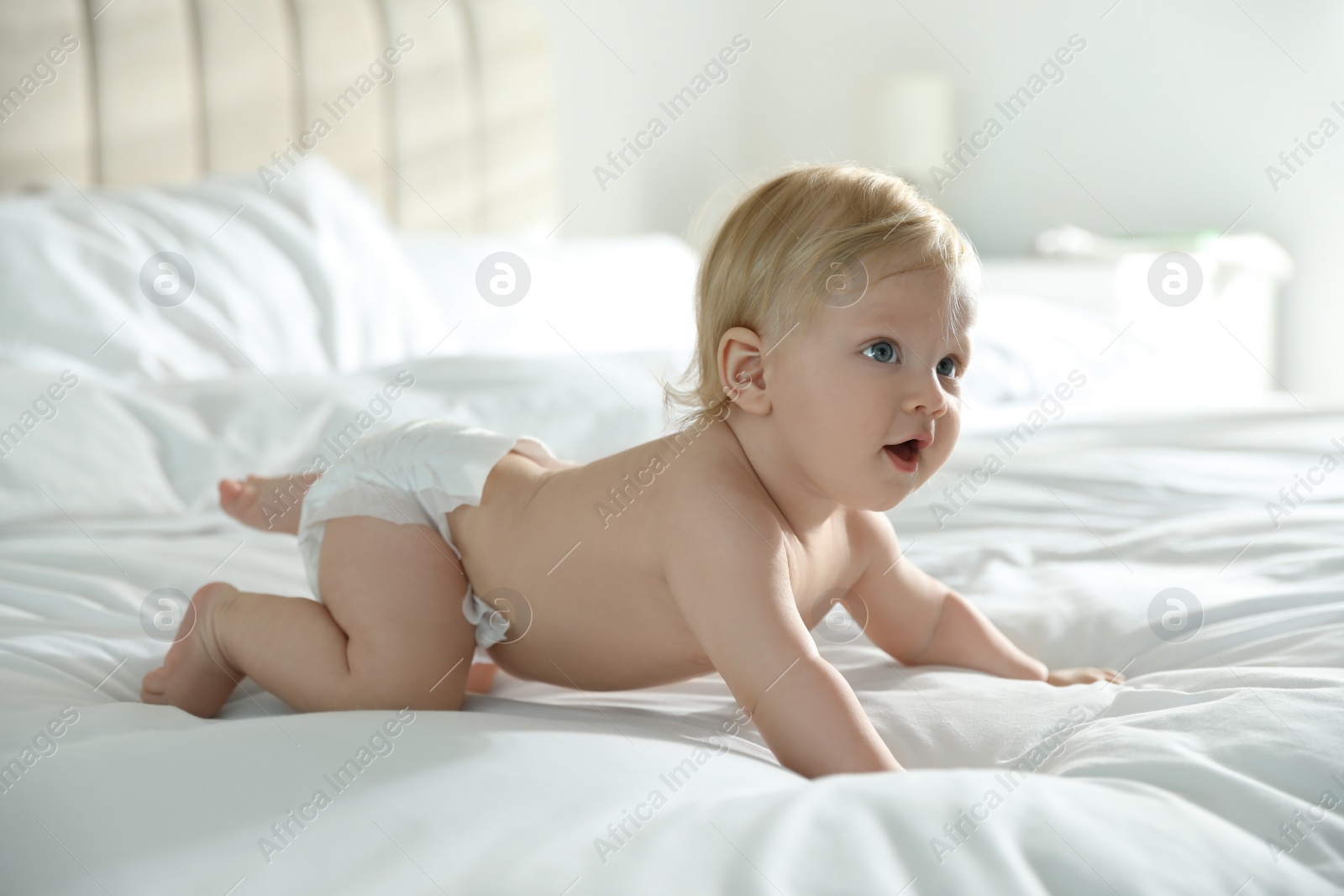 Photo of Cute little baby in diaper on bed at home