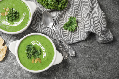 Photo of Tasty kale soup served on grey table, flat lay