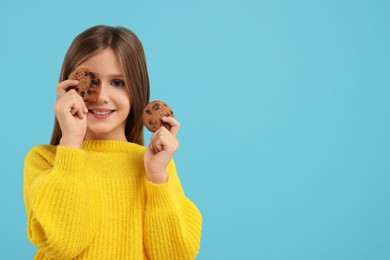 Photo of Cute girl with chocolate chip cookies on light blue background. Space for text