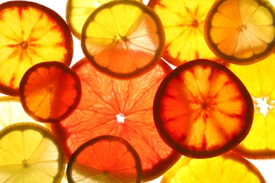 Photo of Illuminated slices of citrus fruits on white background, top view