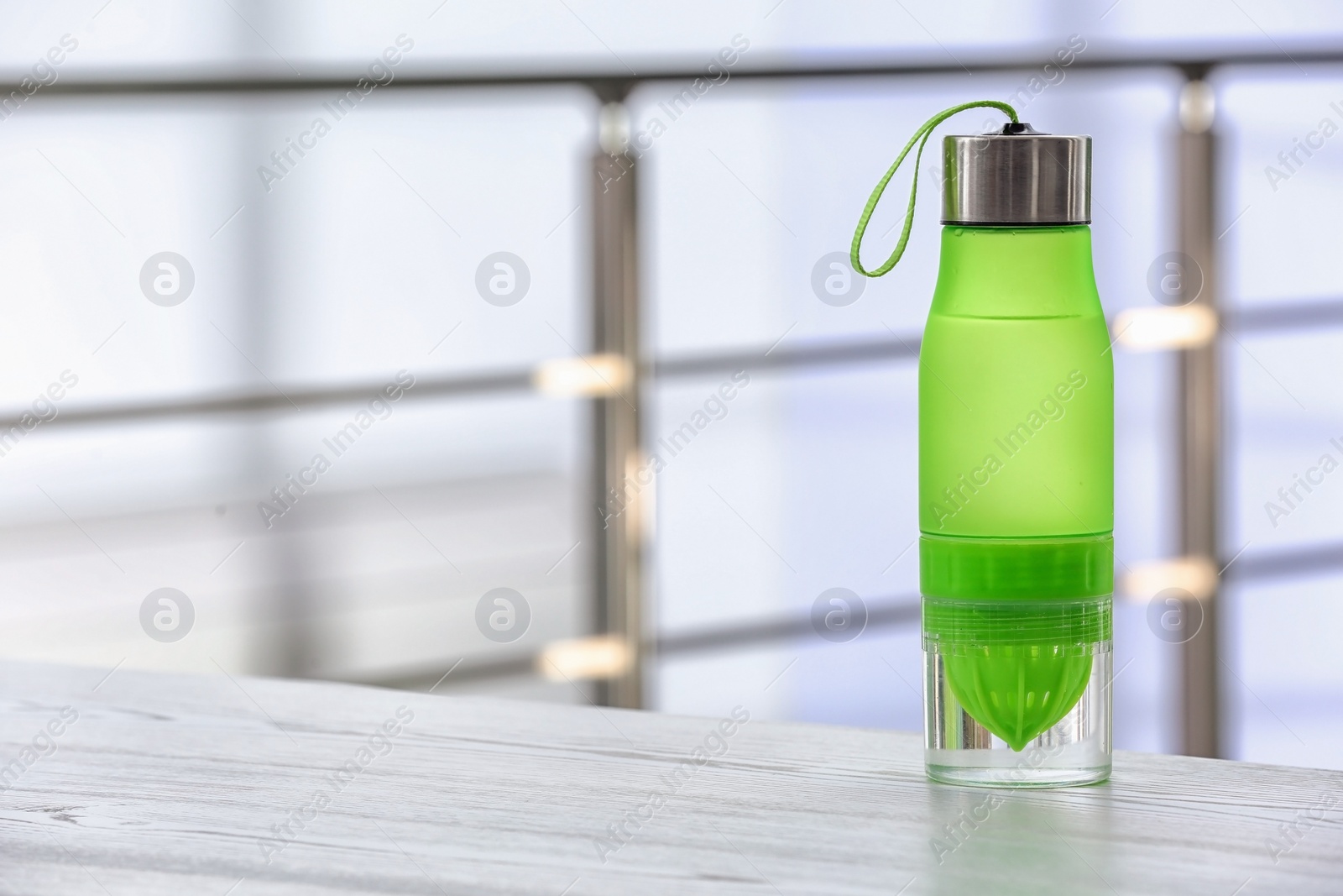 Photo of Sports water bottle on table against blurred background. Space for text