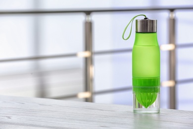 Photo of Sports water bottle on table against blurred background. Space for text