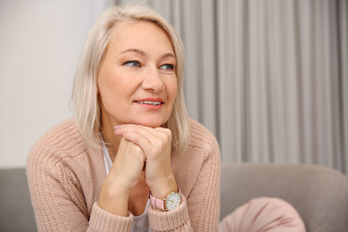 Photo of Beautiful mature woman on sofa at home. Space for text