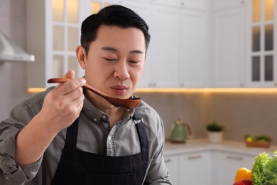 Photo of Cooking process. Man tasting dish in kitchen, space for text