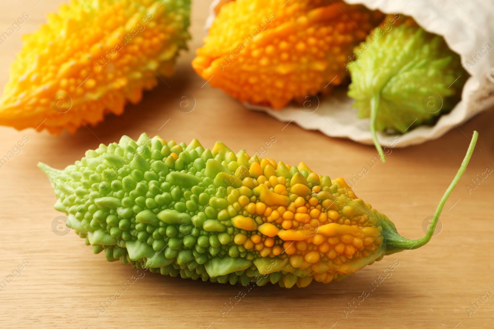 Photo of Fresh bitter melons on wooden table, closeup