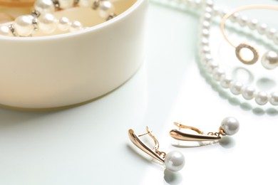 Photo of Elegant golden earrings and other stylish jewelry with pearls on white table