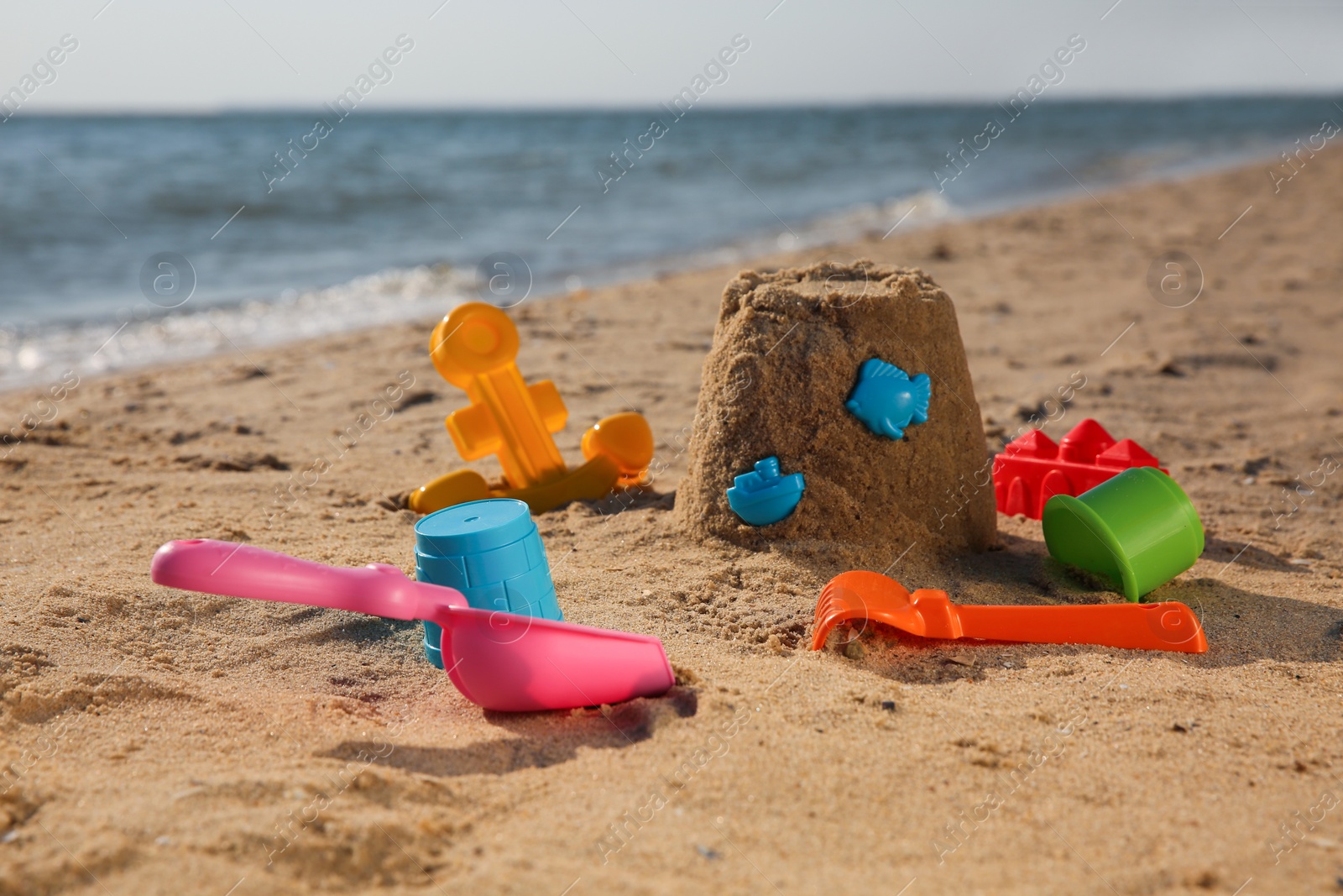 Photo of Set of plastic beach toys on sand near sea. Outdoor play