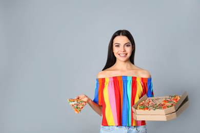 Photo of Beautiful woman with pizza on grey background, space for text