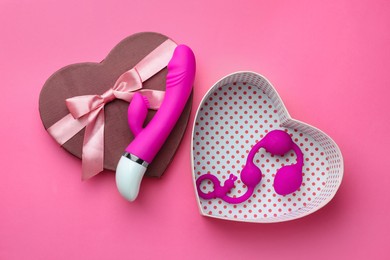 Photo of Gift box with sex toys on pink background, flat lay
