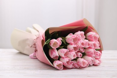 Beautiful bouquet of fresh pink tulips on white wooden table indoors