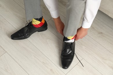 Photo of Man with colorful socks putting on stylish shoes indoors, above view