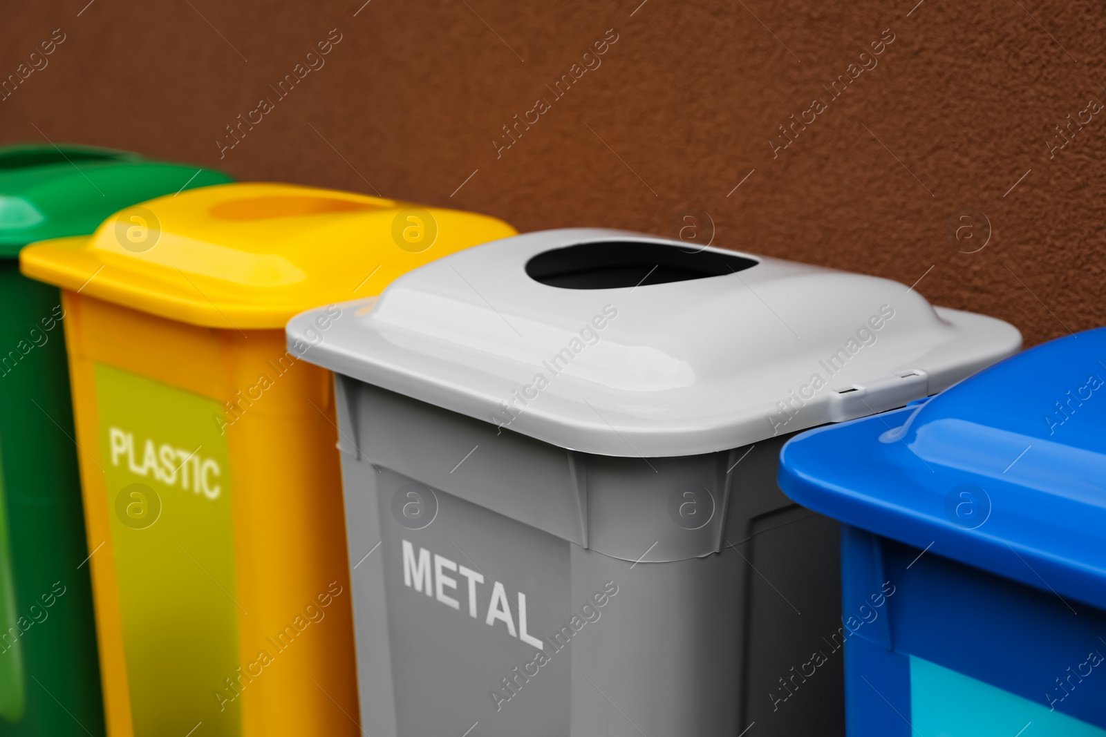 Photo of Many color recycling bins near brown wall, closeup