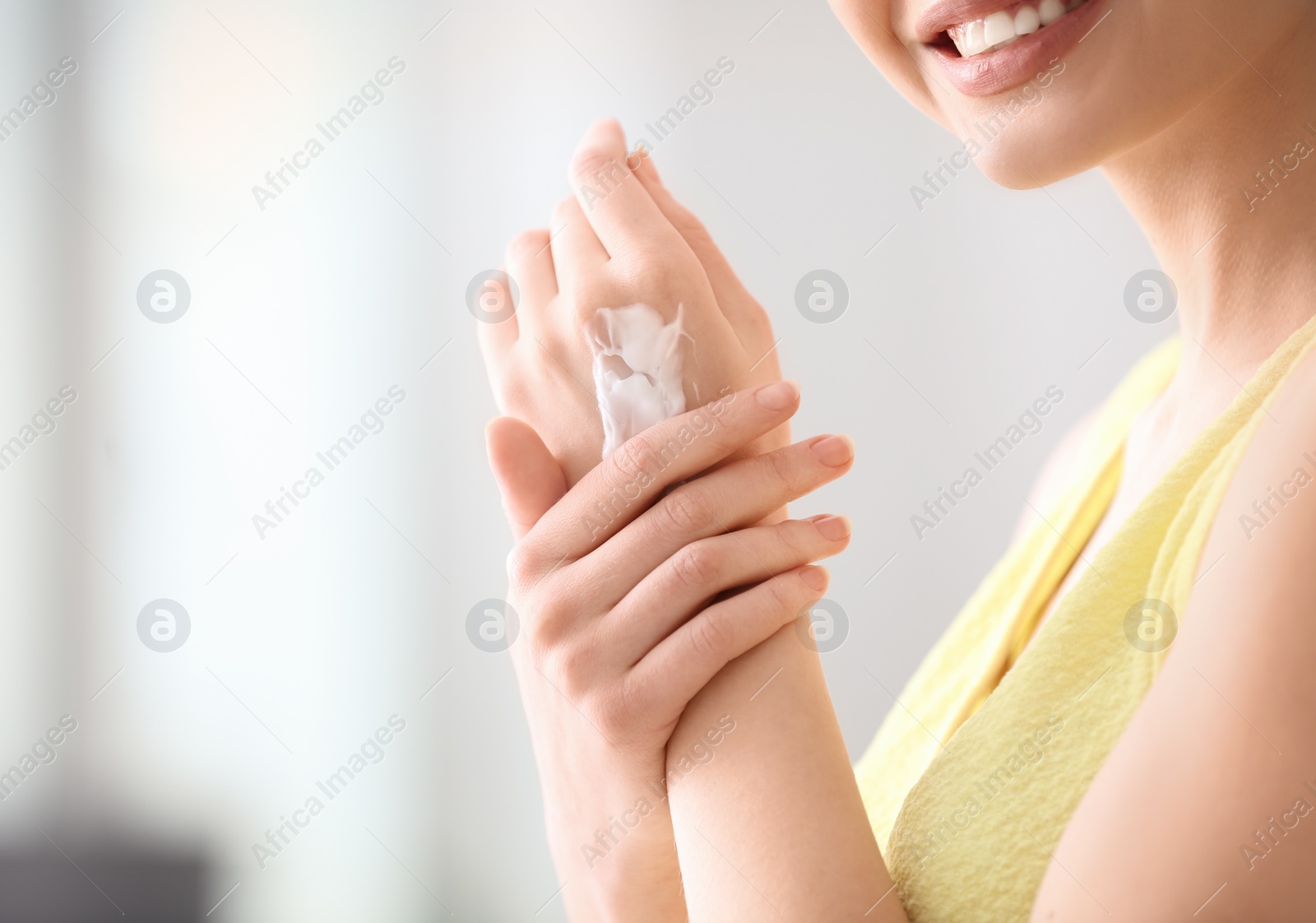Photo of Young woman applying hand cream at home, closeup