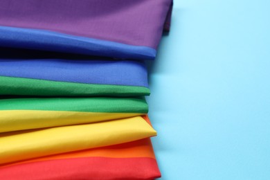 Photo of Rainbow LGBT flag on light blue background, closeup. Space for text