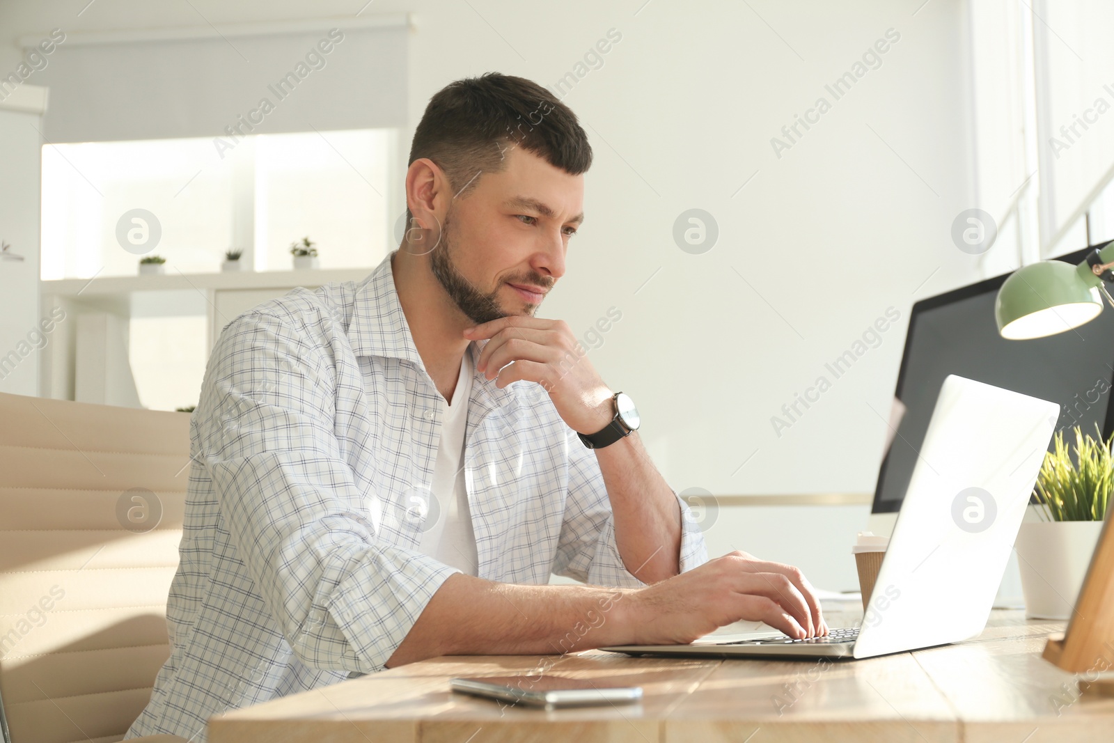 Photo of Freelancer working on laptop at table indoors