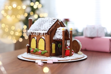 Photo of Beautiful gingerbread house decorated with icing on wooden table indoors
