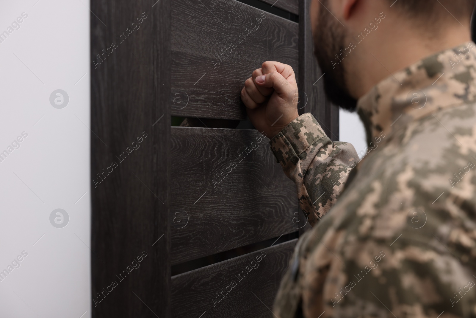 Photo of Military commissariat representative knocking on wooden door, closeup