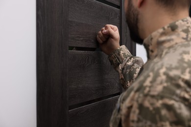 Photo of Military commissariat representative knocking on wooden door, closeup