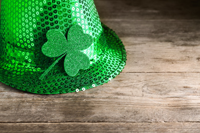 Green leprechaun hat with clover leaf on wooden table, space for text. St. Patrick's Day celebration
