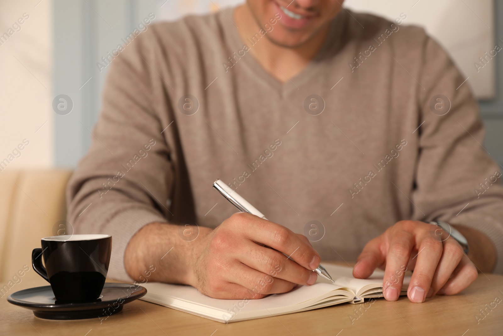 Photo of Man with cup of coffee working at cafe in morning, closeup