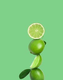 Image of Stacked whole and cut limes on light green background