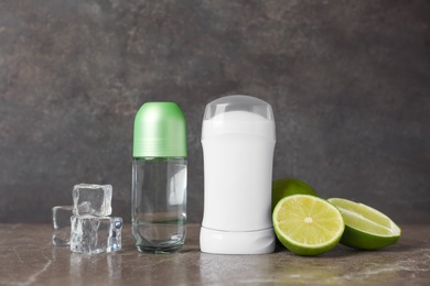 Photo of Different deodorants, limes and ice cubes on dark background