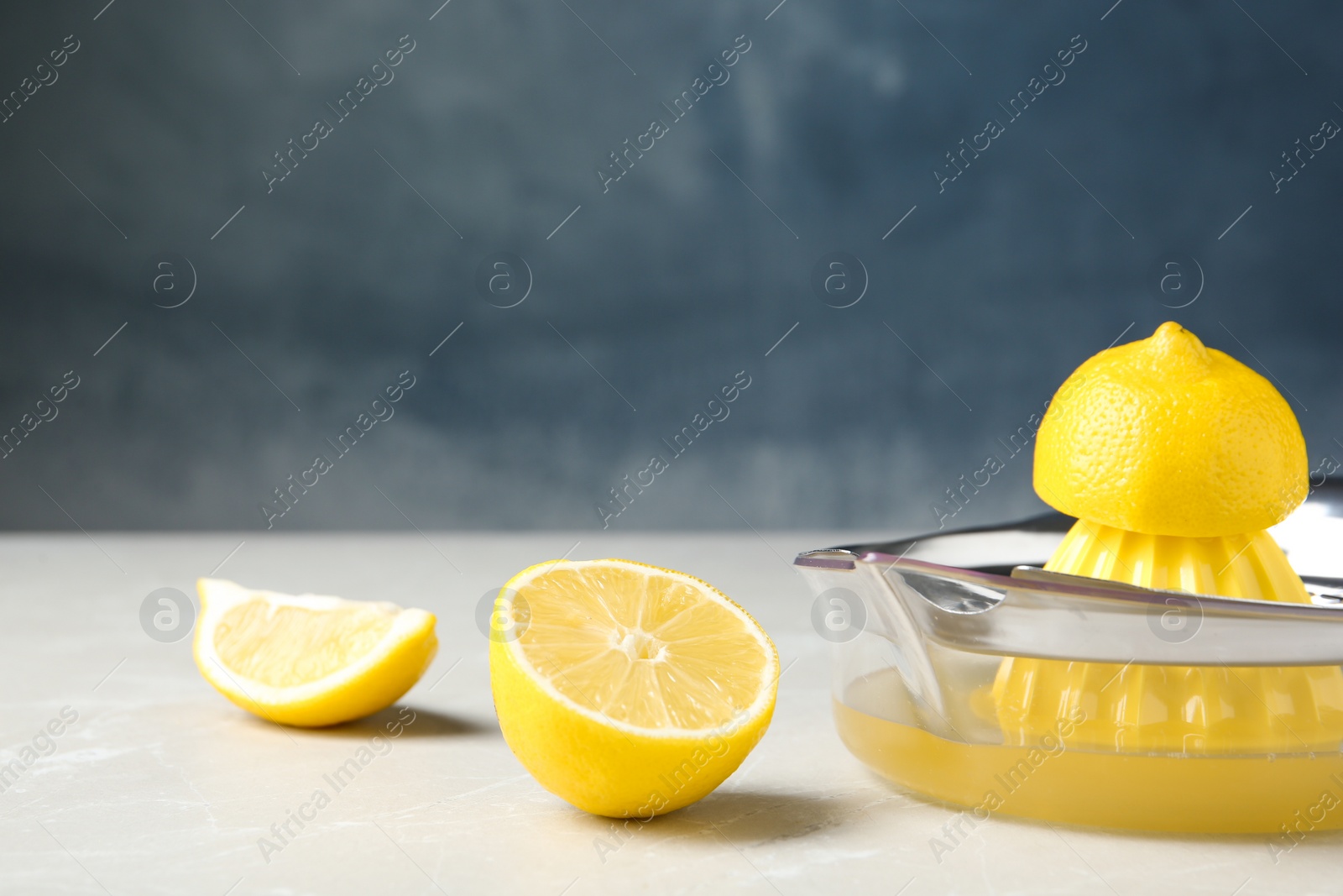 Photo of Slices of lemon and juicer on gray table