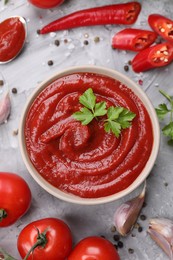 Flat lay composition with organic ketchup in bowl on grey textured table. Tomato sauce