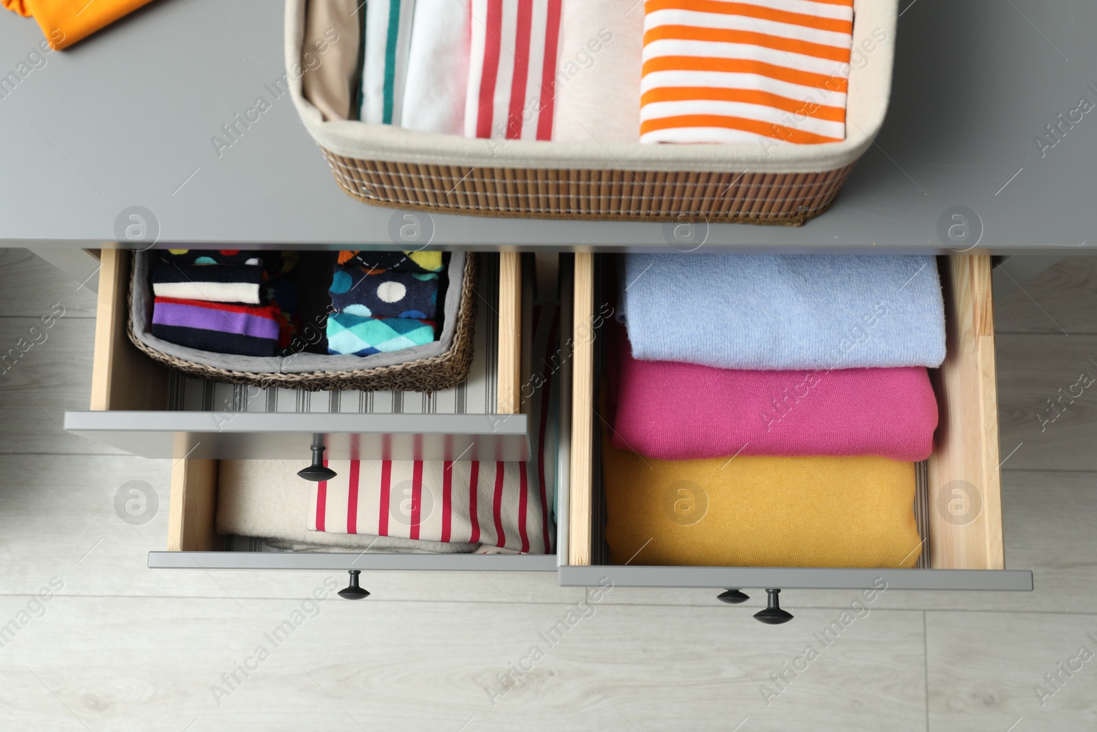 Photo of Chest of drawers with different folded clothes indoors, top view