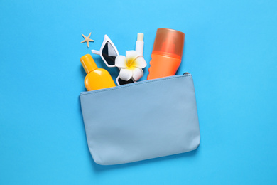 Photo of Sun protection products and sunglasses in bag on blue background