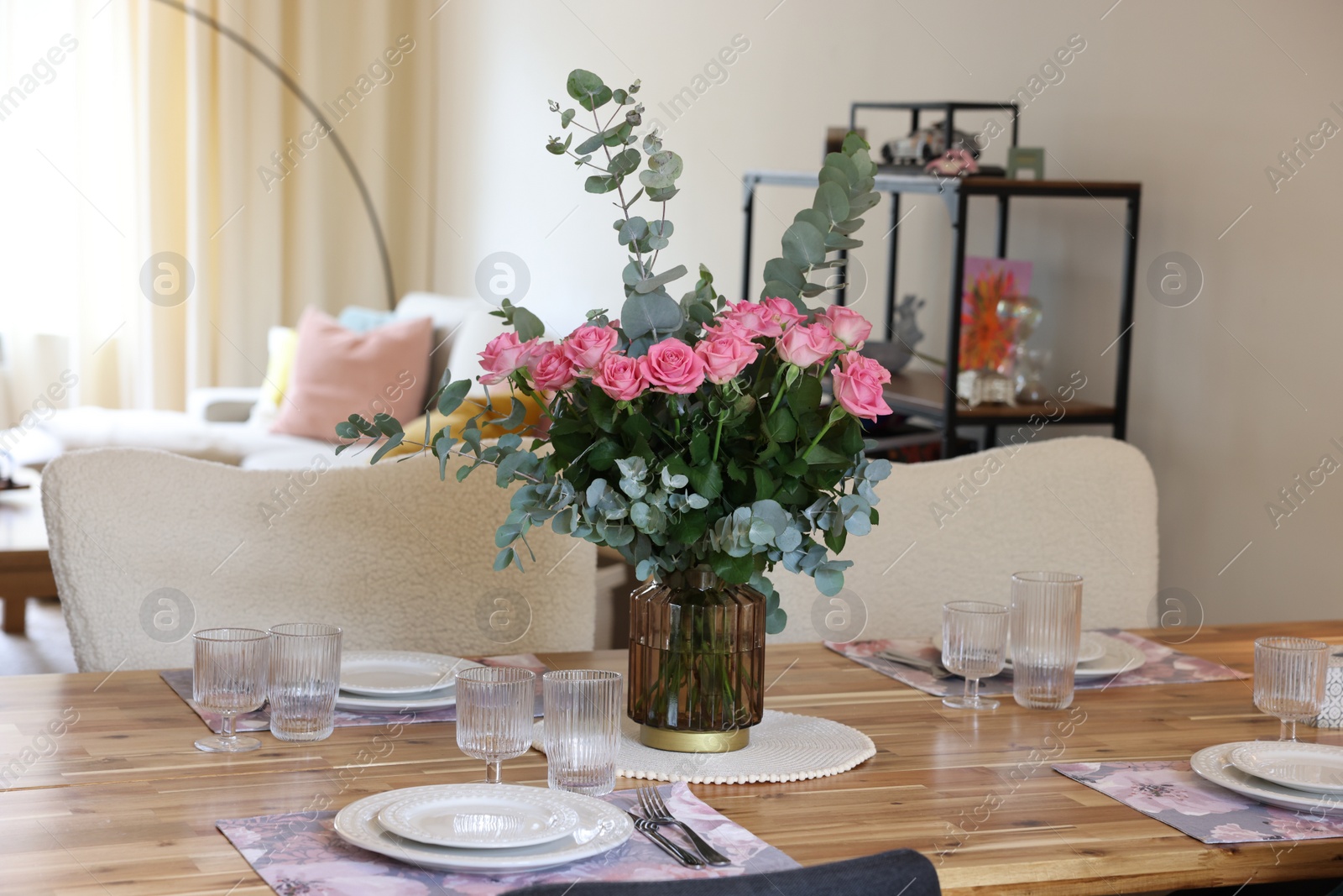 Photo of Beautiful table setting with bouquet in dining room. Roses and eucalyptus branches in vase