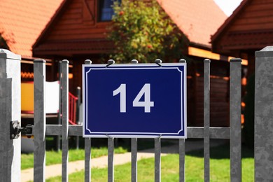 Plate with house number fourteen hanging on iron fence outdoors
