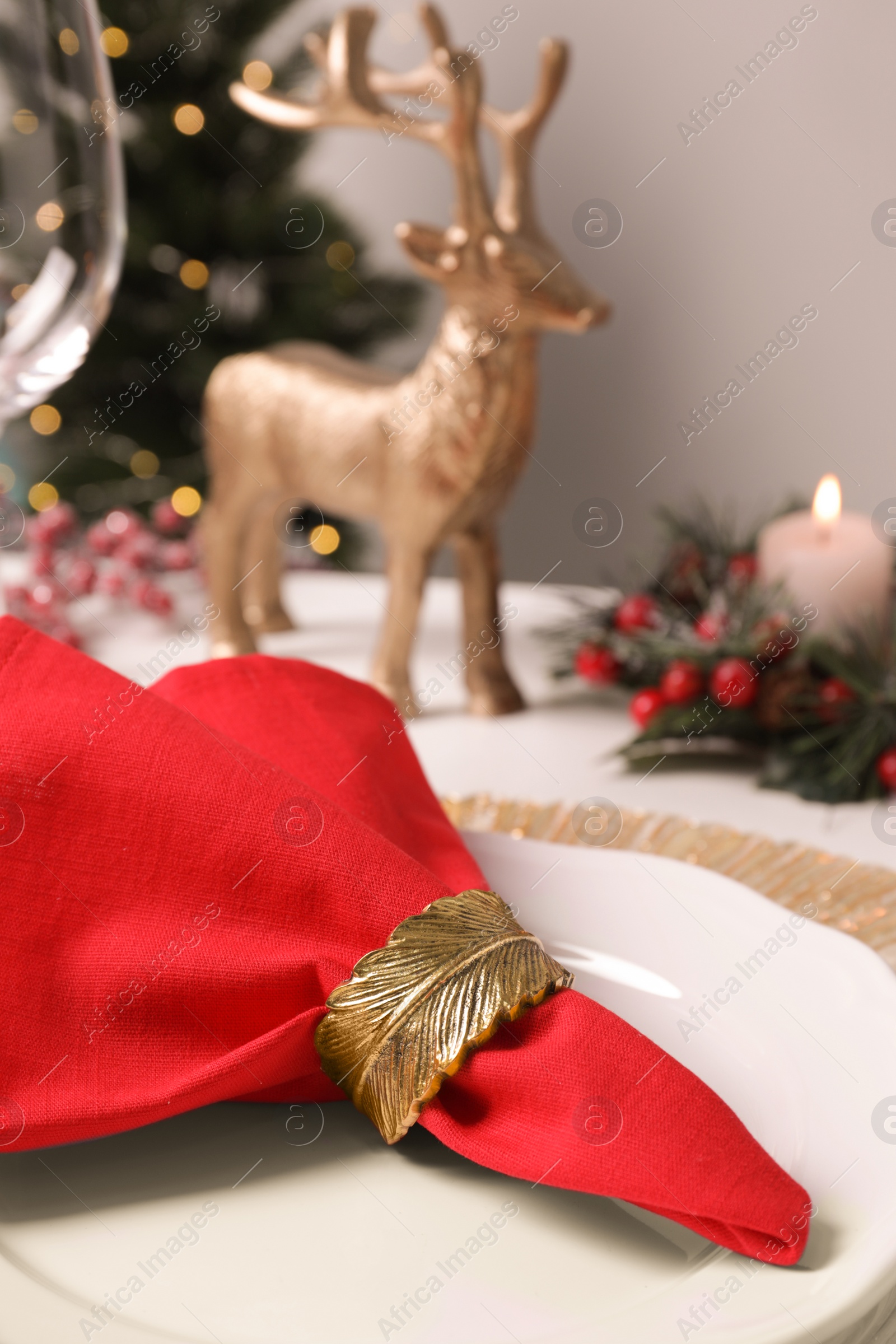 Photo of Plates and red fabric napkin with decorative ring on white table, closeup