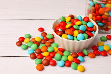 Photo of Tasty colorful candies on white wooden table, space for text