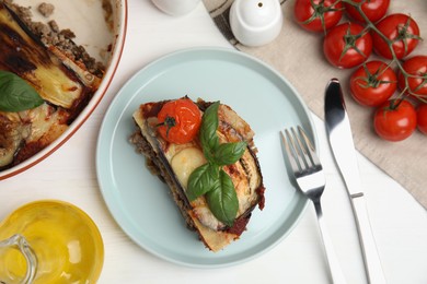 Photo of Plate of delicious eggplant lasagna served on white wooden table, flat lay