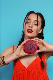 Photo of Young woman with fresh pitahaya on light blue background. Exotic fruit