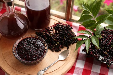 Photo of Elderberry drink and jam with Sambucus berries on table near window