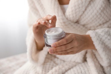 Photo of Woman with jar of moisturizing cream indoors, closeup