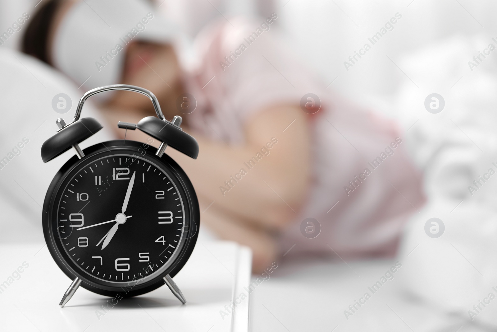 Photo of Woman sleeping at home in morning, focus on alarm clock. Space for text