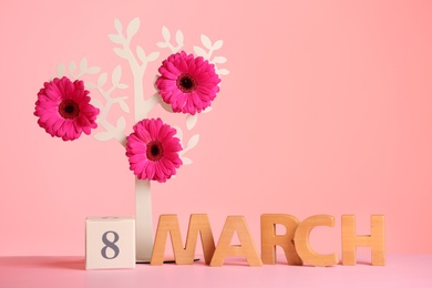 Photo of Composition with decorative tree and flowers on table against color background, space for text. International Women's Day