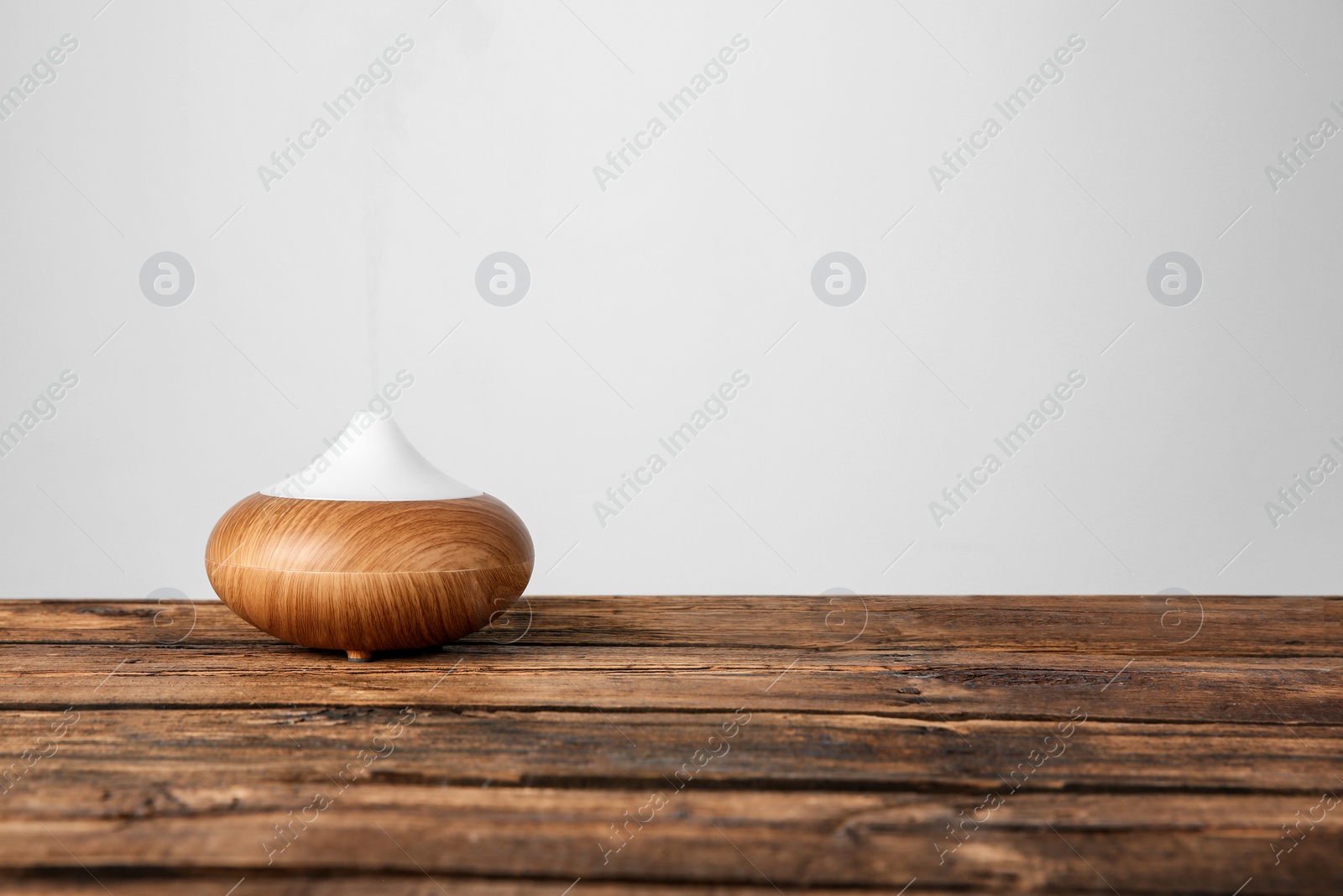 Photo of Aroma oil diffuser lamp on table against light background