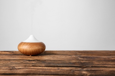 Photo of Aroma oil diffuser lamp on table against light background