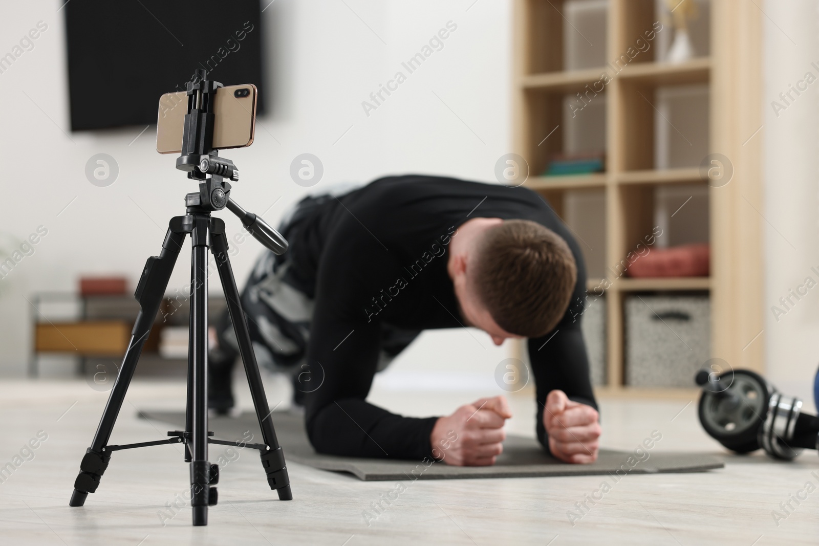 Photo of Trainer streaming online workout with phone at home