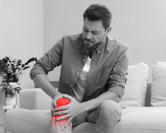 Image of Man suffering from rheumatism at home. Black and white effect with red accent in painful area