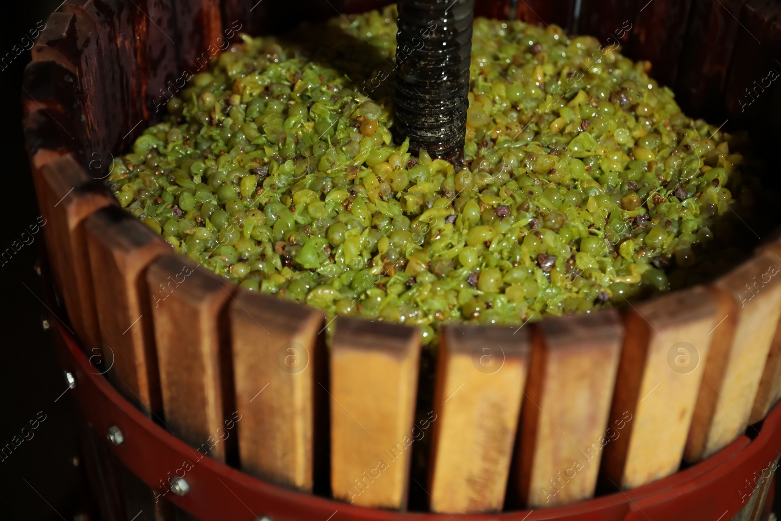 Photo of Wooden wine press with grape must indoors, closeup